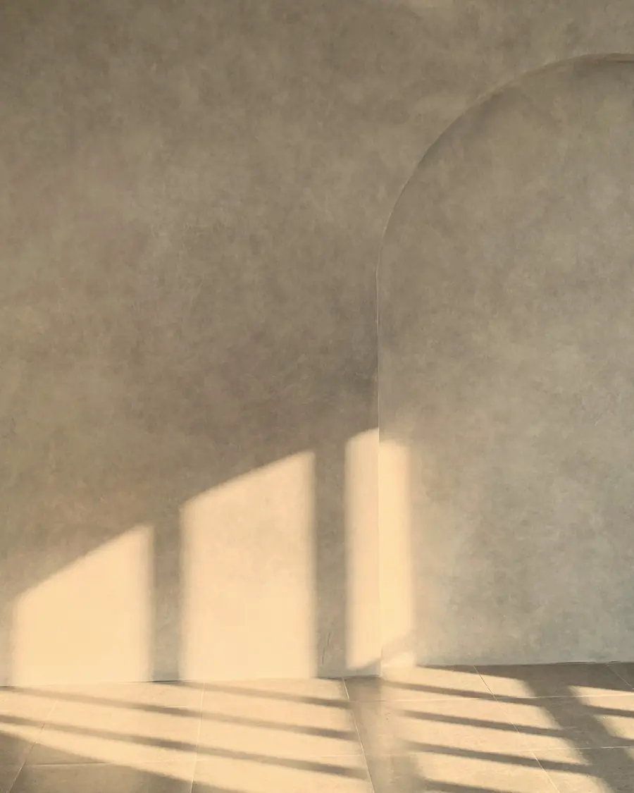 Parede clara do consultório com um arco e faixas de sol da tarde.